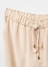 Pantalón color beige de corte recto y fluido, con cintura elástica ajustable con lazo.