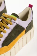 Zapatillas deportivas de cuero color beige con detalles en lila y amarillo.