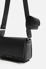 Bandolera negra con acabado grabado, compartimento principal con cierre mediante solapa imantada, bolsillo interior con cierre mediante cremallera, bolsillo frontal con cierre mediante cremallera, asa de hombro ajustable y monedero.