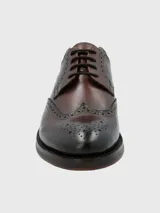 Zapato de vestir marrón oscuro con cordones, estilo Oxford, con detalles de perforaciones y costuras en cuero.