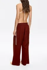 Pantalón de corte jogger color ladrillo, confeccionado en mezcla de lino, largo tobillero, con maxibolsillos tipo alforja. Cintura elástica pespunteada y ajustable con cordones de tejido.