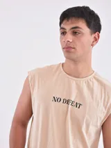 Musculosa color beige con estampado de calavera, rayos y la frase "No Defeat". Corte oversize.
