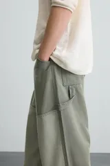 Pantalón de jean color verde con diseño de bloques de color en diferentes tonos de verde, corte amplio, tiro alto, cinco bolsillos y presilla para herramientas en la pierna.