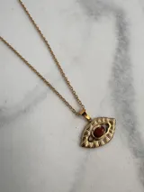 Collar dorado con cadena de eslabones y dije en forma de ojo con piedra color ladrillo en el centro.