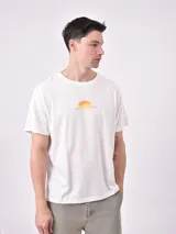 Remera color beige con cuello redondo y manga corta. Estampado en el pecho con un sol naciente y la frase "Soul of the Desert".