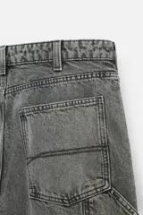 Pantalón color marrón con efecto lavado, corte relaxed fit, cinco bolsillos, aplicación de tira y bolsillo multifunción en perneras, cierre frontal con cremallera y botón.