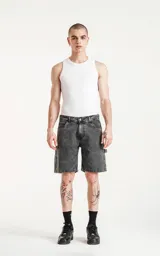 Bermuda de denim gris con efecto lavado, calce oversize estilo carpintero y bolsillo lateral.