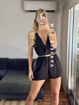 Mono corto negro con escote en V cruzado, sin mangas y con cinturón dorado.