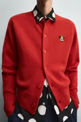 Cárdigan rojo de punto con cuello redondo, manga larga y cierre frontal con botones. Tiene un parche de Minnie Mouse en el pecho.