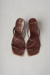 Sandalias de tacón color marrón chocolate con capellada trenzada, punta cuadrada y dos tiras finas sobre el empeine. Tacón cuadrado.