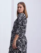 Vestido corto de rayón con estampado floral en tonos azules y blancos. Tiene escote en V, mangas 3/4 con puño, cintura con lazo de ajuste y borlas.