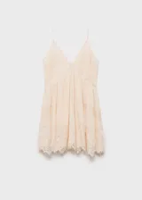 Vestido corto color crema con tirantes finos y escote en V, con detalles de encaje en escote y ruedo.