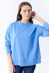 Buzo deportivo celeste de corte holgado, con cuello redondo y mangas largas.