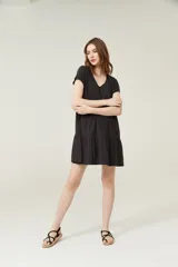 Vestido negro corto con cuello en V, manga corta y falda con volados.