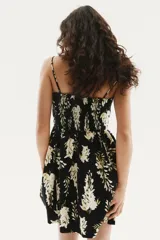 Vestido corto negro con estampado floral blanco y amarillo, de breteles finos, escote corazón, cuerpo entallado, espalda fruncida, cintura marcada con elástico y falda con vuelo.