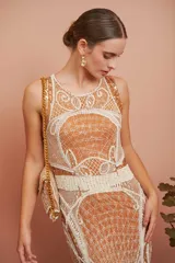 Vestido corto color ocre con bordado de motivos geométricos en color crema. Sin mangas, con cuello redondo y corte ajustado. Largo a la rodilla.