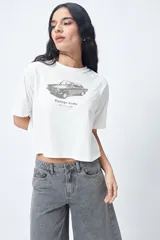 Remera cropped blanca de mangas ranglan con estampa frontal de un auto antiguo y texto "Vintage Gems / retro car club".