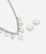 Conjunto de collar corto con cadena de eslabones plateados y colgantes de corazones con diferentes texturas y diseños. Incluye un par de aros tipo argolla con forma de corazón.