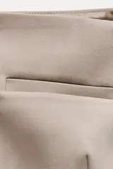 Chaleco color beige de escote recto y tirantes finos. Presenta un falso bolsillo de vivo en el delantero y cierre frontal con botones forrados.