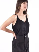 Musculosa negra con escote en V y botones frontales. Los tirantes son ajustables con hebillas metálicas.