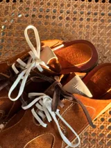 Zueco de cuero color marrón con cordones y suela de goma.