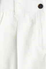 Short blanco de corte sastrero con cierre y botón, bolsillos al bies y bolsillo trasero decorativo. Piernas con pinzas y pliegues adelante y atrás.
