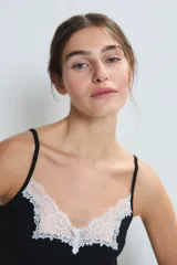Camisón corto negro con breteles finos y escote en V con detalle de encaje blanco.
