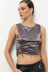 Musculosa negra de satén con cuello redondo y cordón ajustable en el lateral izquierdo para fruncir la prenda.