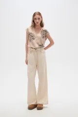 Pantalón de jean color beige, de tiro alto, corte palazzo y estilo paper bag.