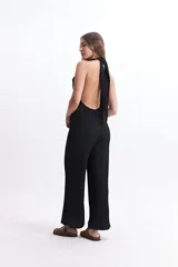 Mono largo color crudo, con escote halter, espalda descubierta y corte palazzo.