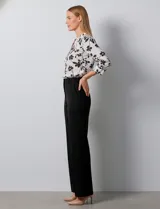 Blusa de gasa blanca con estampado floral en negro. Presenta cuello a la base con escote en V y abertura con botones. Las mangas son largas y se pueden ajustar a tres cuartos.