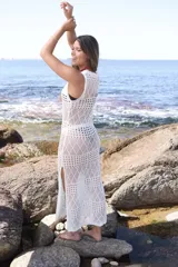 Vestido largo de encaje blanco, sin mangas, con acabado acanalado y detalles de flecos en la parte inferior.