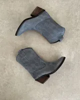 Bota corta de gamuza negra con bordados en hilo negro en la caña y puntera. Taco cuadrado y bajo.