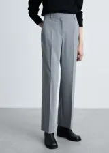Pantalón de vestir gris con diseño recto, tiro medio, trabillas y cierre oculto con gancho, botón y cremallera.