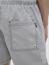 Short de baño celeste y blanco a rayas verticales, confeccionado en tejido seersucker. Cuenta con cintura elástica con cordón ajustable, bolsillos delanteros y un bolsillo trasero.