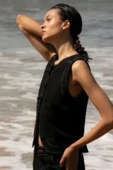 Chaleco de denim negro sin mangas con cuello redondo y costuras en contraste. Presenta un parche de cuero marrón en la parte posterior con el logo de la marca Be Ganesha. Confeccionado en tejido de algodón.