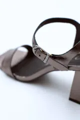Sandalias de cuero charol negro con tira delgada sobre los dedos, pulsera con hebilla al tobillo y tacón cuadrado.