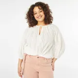 Blusa blanca con bordado calado, escote con lazo y mangas 3/4 abullonadas.