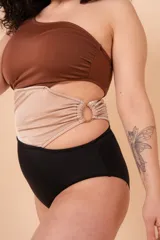 Malla entera de un solo hombro color marrón, beige y negro. Presenta aperturas laterales con aro y está confeccionada con tela que contiene fibra LYCRA® XTRA LIFE™.