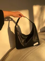 Cartera tipo baguette negra de lona semi impermeable con cierre metálico y forrería de gross con bolsillo interno.