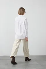 Camisa blanca de algodón con diseño utilitario y calce relajado. Presenta dos bolsillos frontales de estilo cargo con tapa y costuras a contratono.
