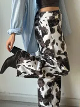 Pantalón de jean con estampado animal print de vaca en tonos marrón y blanco, de corte recto.