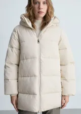 Campera puffer larga color beige con capucha, cierre frontal con cremallera y bolsillos laterales con cremallera.