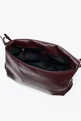 Bolso bandolera tipo sobre color borgoña, con asa fina y cierre imantado con solapa. Incluye bolsillo interior con cierre de cremallera metálica.