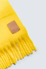 Bufanda color crema confeccionada en tejido con lana y acabado cepillado. Tiene flecos en los extremos.