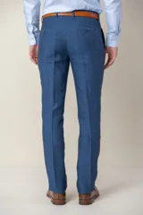 Pantalón de vestir azul marino, de corte recto, confeccionado en lino. Se ajusta a la cintura con cinturón de cuero marrón.