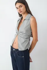 Top sin mangas con escote pico, frunce delantero y bajo ligeramente abierto.
