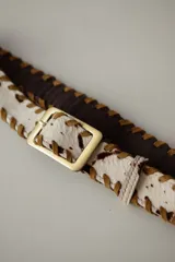 Cinturón de cuero color bordó con costura de tientos en color azul oscuro a lo largo de los bordes. Posee hebilla metálica rectangular plateada.