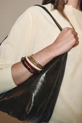Set de cinco pulseras rígidas para mujer, que incluyen dos pulseras metálicas doradas y tres pulseras de resina en color blanco, rojo y marrón, con apliques metálicos labrados.