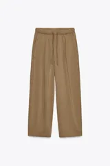 Pantalón color marrón claro, de tiro medio, corte ancho y largo tobillero. Cuenta con cintura elástica ajustable con cordones y bolsillos laterales ocultos en la costura.